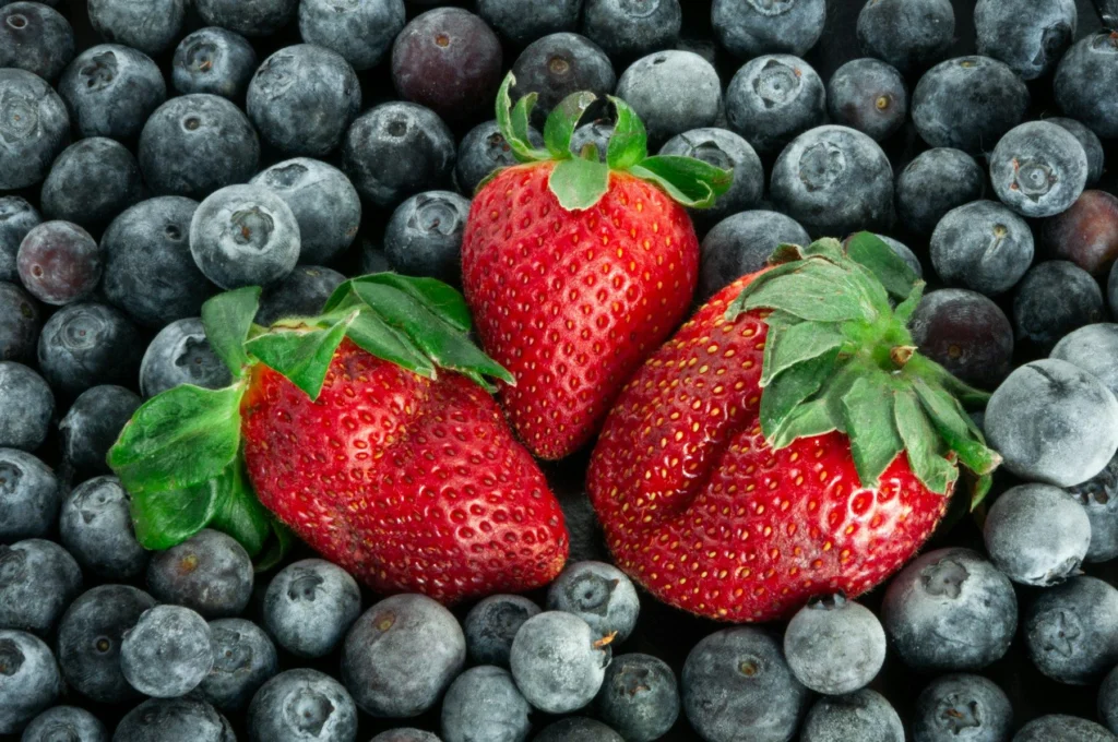 Fresh strawberries resting on blueberries